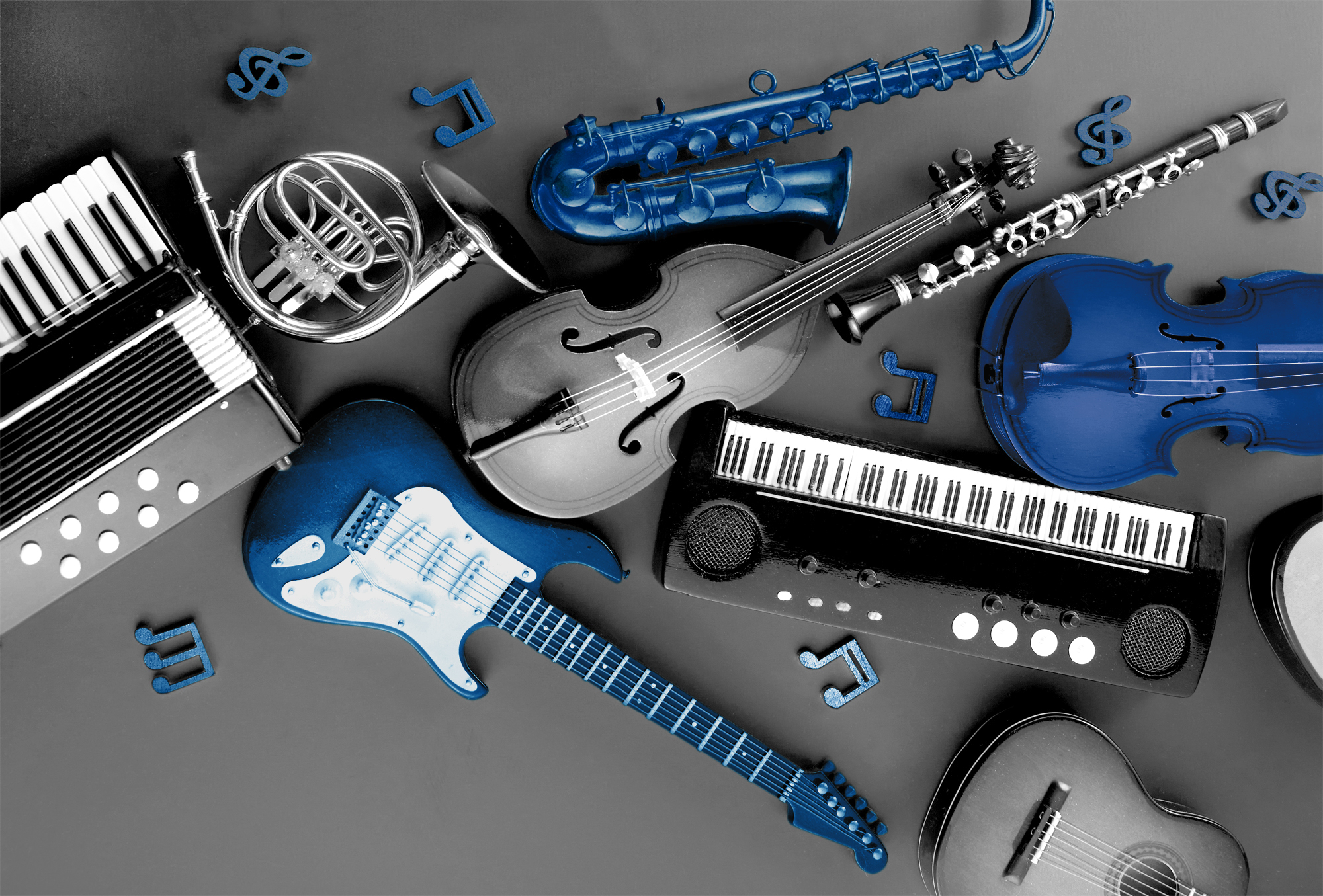 verschiedene Musikinstrumente liegen nebeneinander in schwarz-weiß mit Farbakzente in Blau