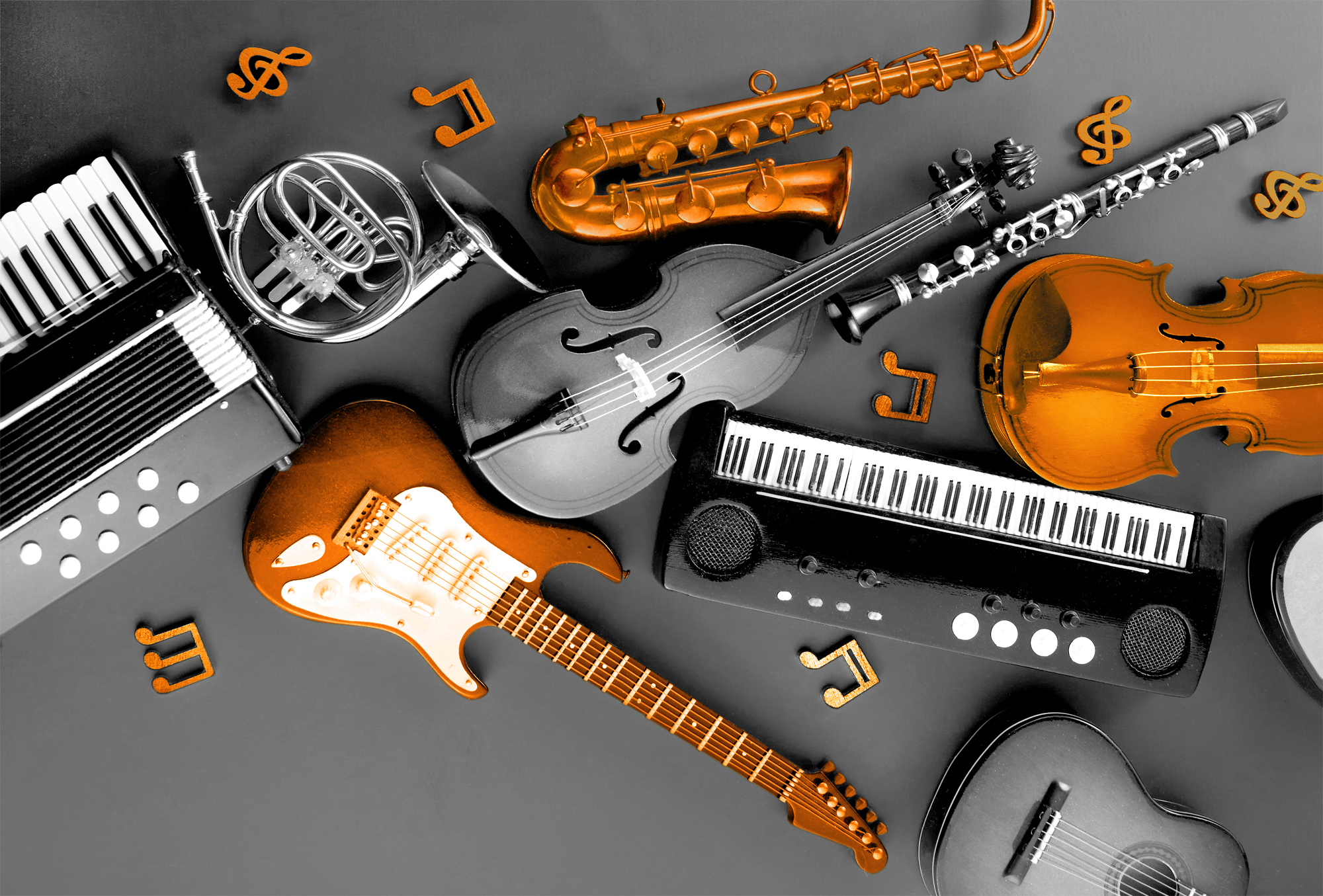 verschiedene Musikinstrumente liegen nebeneinander in schwarz-weiß mit Farbakzente in Orange