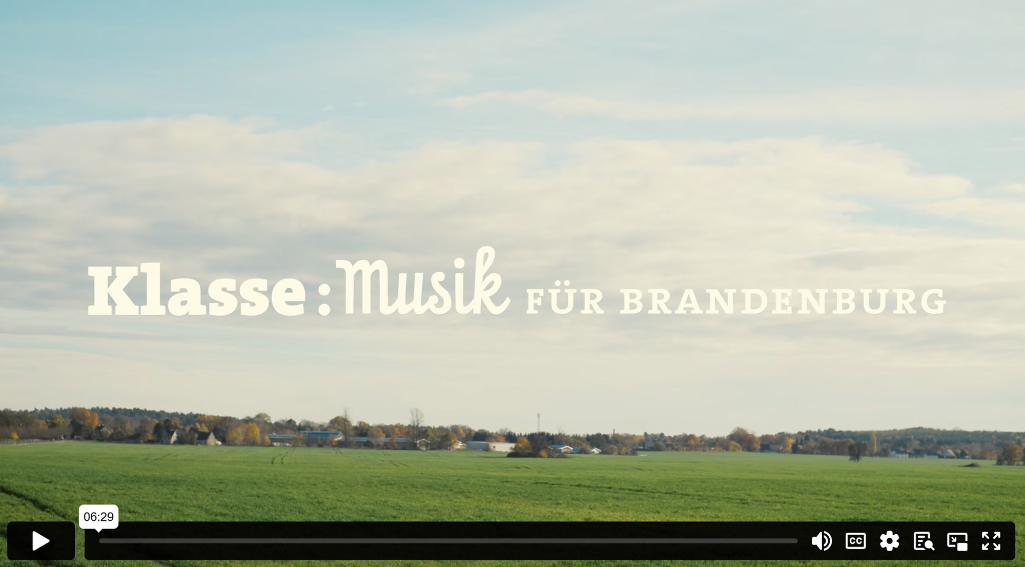 Startbild des Kurzfilm Klasse:Musik in Brandenburg zeigt eine Kulturlandschaft in Brandenburg mit einem grünen Feld und Bäume am Feldrand.